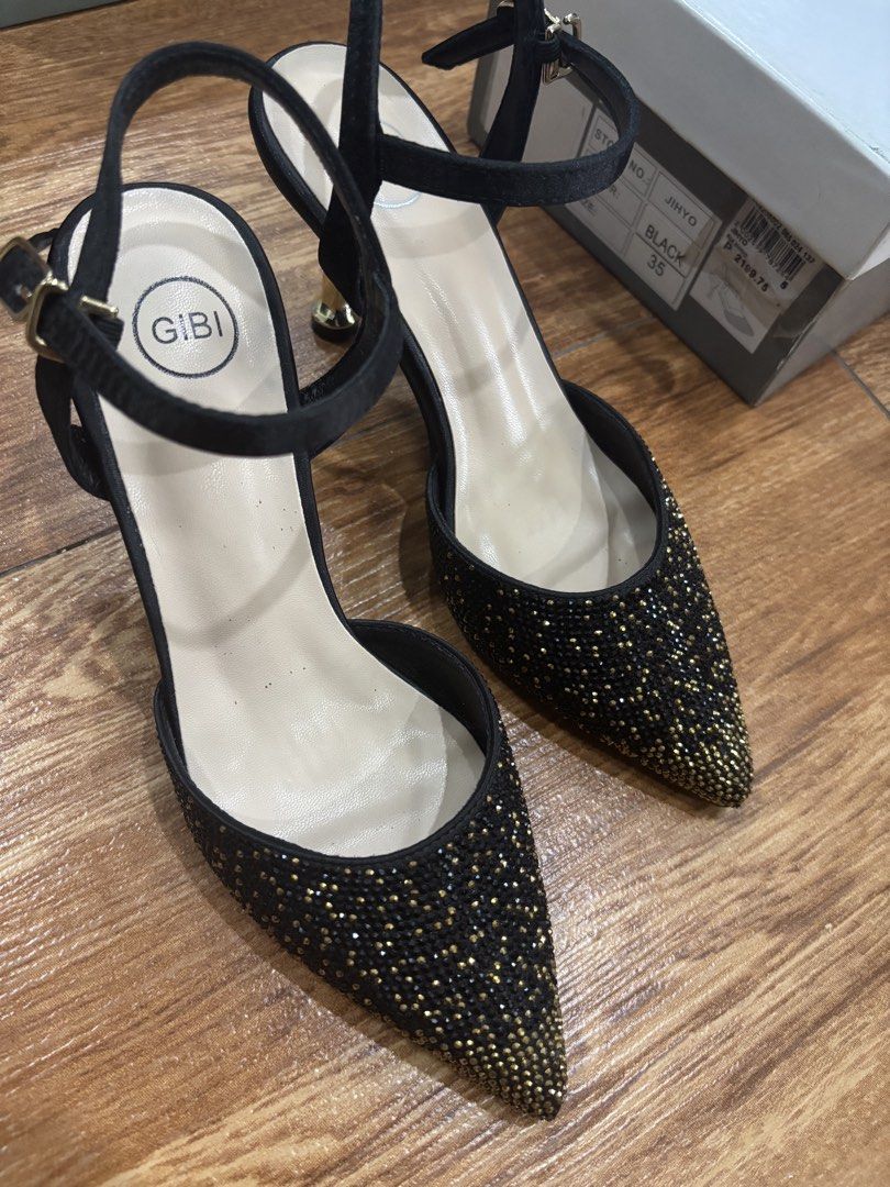 Gibi Black Heels Size 35 (Category: Heels) located in San Juan City. Submitted by ____aiceee____ (Listing ID 1424039632, Image 2). Description: Elegant black heels from Gibi, size 35. Features a pointed toe design with sparkling embellishments. Includes an ankle strap with a buckle closure. The heels have a gold-colored accent. The soles are black. The heels come with the original box. Bought for P2,199.75 / Used once .
