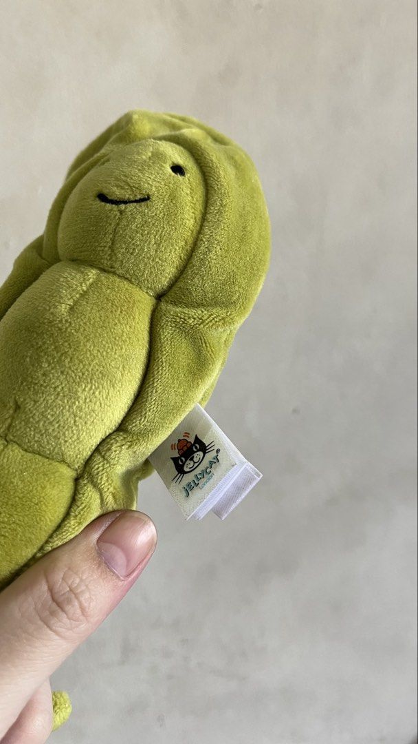 Jellycat Amuseable Pea in Pod Plush Toy (Category: Plushies & Soft Toys) located in Quezon City. Submitted by jellycooties (Listing ID 1423992205, Image 2). Description: - Jellycat Amuseable Pea in Pod plush toy - Features a smiling pea character - Nestled inside a soft, green pod - Includes the Jellycat tag - Has a loop at the top and a small tail at the bottom - Made of soft, plush material.
