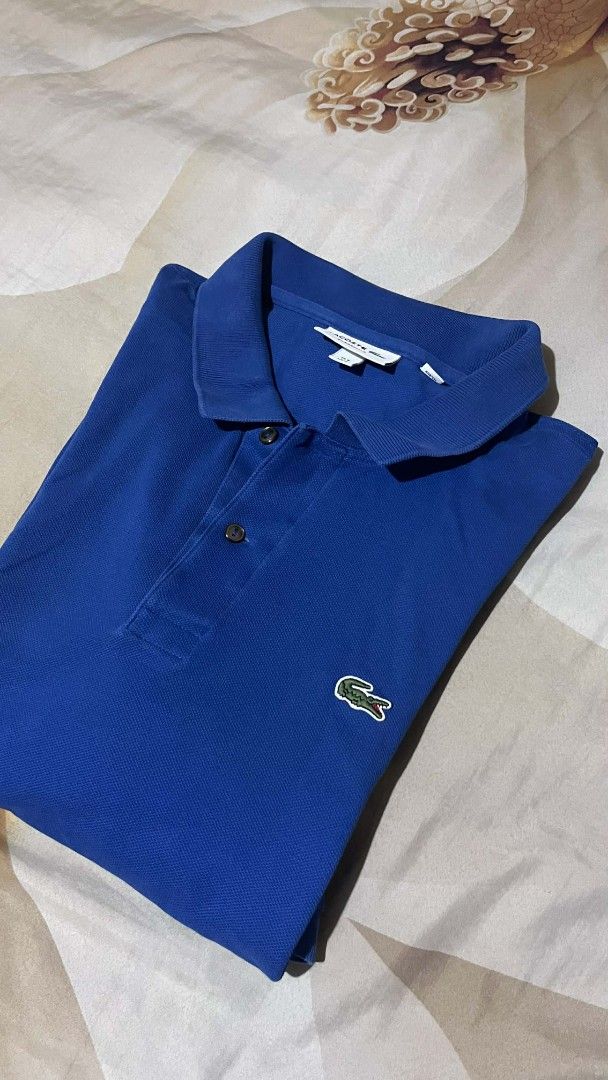 Lacoste Classic Fit Polo Shirt (Category: Tshirts & Polo Shirts ) located in Cebu City. Submitted by markmeta213 (Listing ID 1424058926, Image 2). Description: Classic Lacoste polo shirt in a vibrant blue color. Features the iconic Lacoste crocodile logo on the chest. The shirt has a classic collar and button-up placket. The tag indicates a size of 6. Made with a comfortable fabric, perfect for casual wear..