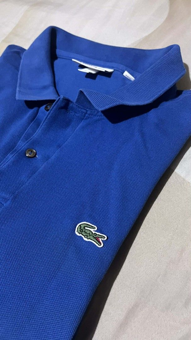 Lacoste Classic Fit Polo Shirt (Category: Tshirts & Polo Shirts ) located in Cebu City. Submitted by markmeta213 (Listing ID 1424058926, Image 3). Description: Classic Lacoste polo shirt in a vibrant blue color. Features the iconic Lacoste crocodile logo on the chest. The shirt has a classic collar and button-up placket. The tag indicates a size of 6. Made with a comfortable fabric, perfect for casual wear..