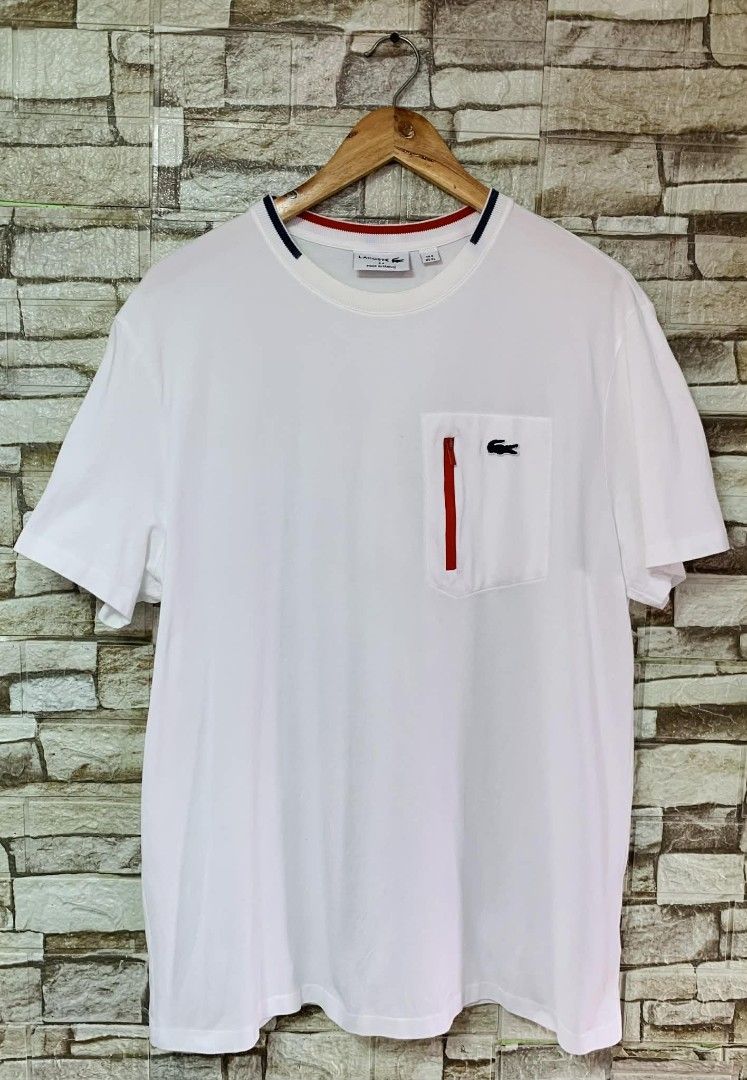 Lacoste White Pocket T-Shirt (Category: Tshirts & Polo Shirts ) located in Caloocan City. Submitted by vintstreets (Listing ID 1424102952, Image 2). Description: LACOSTE 💎Dimes: Width: 22 Length: 29 💎Condi&CR: 9.3/10 📍issue: dot stain hindi ganun ka visible 📍dirt sa likod (see details) ⬇️ 💎solid condition nito - Lacoste T-shirt - Size: US XL (FR 6) - Features a pocket with a red zipper - Crew neck with red and navy blue accents - Lacoste log
