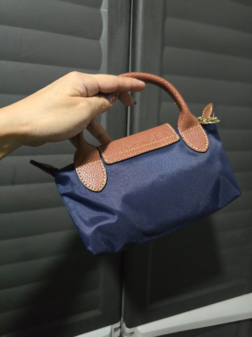 Longchamp Le Pliage Handbag (Category: Luxury Bags & Wallets) located in Manila. Submitted by muliph (Listing ID 1424006157, Image 2). Description: - Navy blue Longchamp Le Pliage handbag - Classic design with brown leather accents - Top handle and flap closure - Gold-tone button and zipper pull - Durable nylon material.