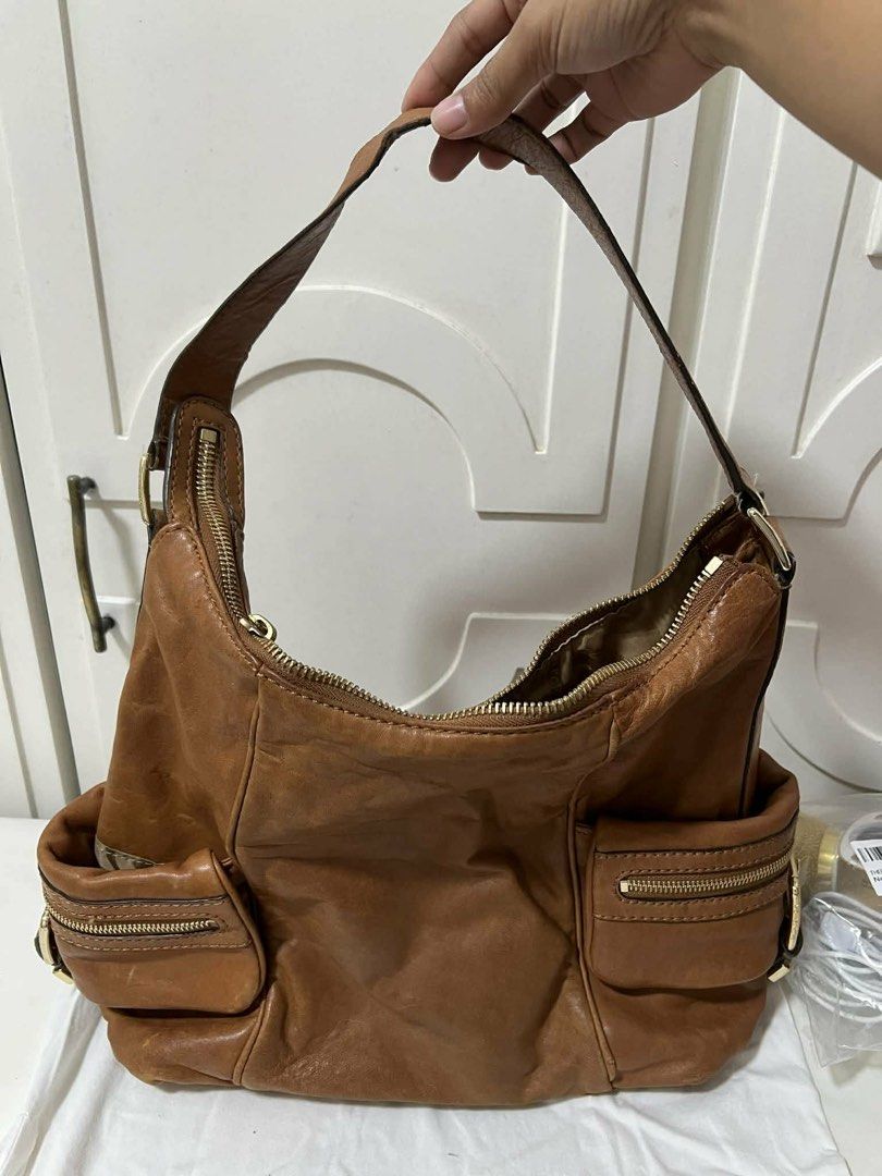 Michael Kors Leather Hobo Bag (Category: Luxury Bags & Wallets) located in Cavite. Submitted by sjcat (Listing ID 1423972818, Image 2). Description: - SELLING LOW, just need funds Authentic Michael Kors hobo bag - Crafted from genuine brown leather - Spacious main compartment with zipper closure - Two exterior pockets with zipper closures - Signature MK logo charm - Comfortable shoulder strap - Elegant gold-tone hardware.