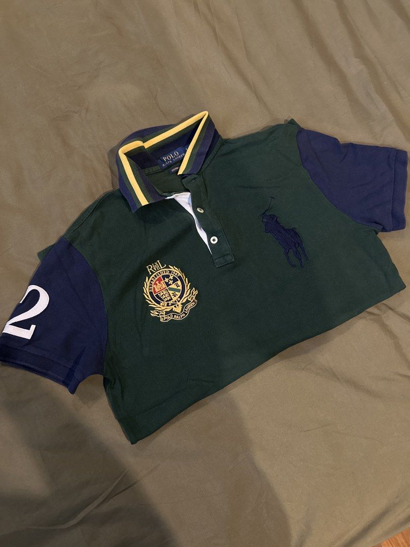 Ralph Lauren Polo Shirt (Category: Tshirts & Polo Shirts ) located in Manila. Submitted by knnyyyyy (Listing ID 1424131492, Image 1). Description: - Ralph Lauren polo shirt - Color: Green and navy blue - Classic polo collar with yellow and navy stripes - Features the iconic Ralph Lauren logo on the chest - Includes a crest on the left side - Navy blue sleeves with the number "2" - Button-up placket.