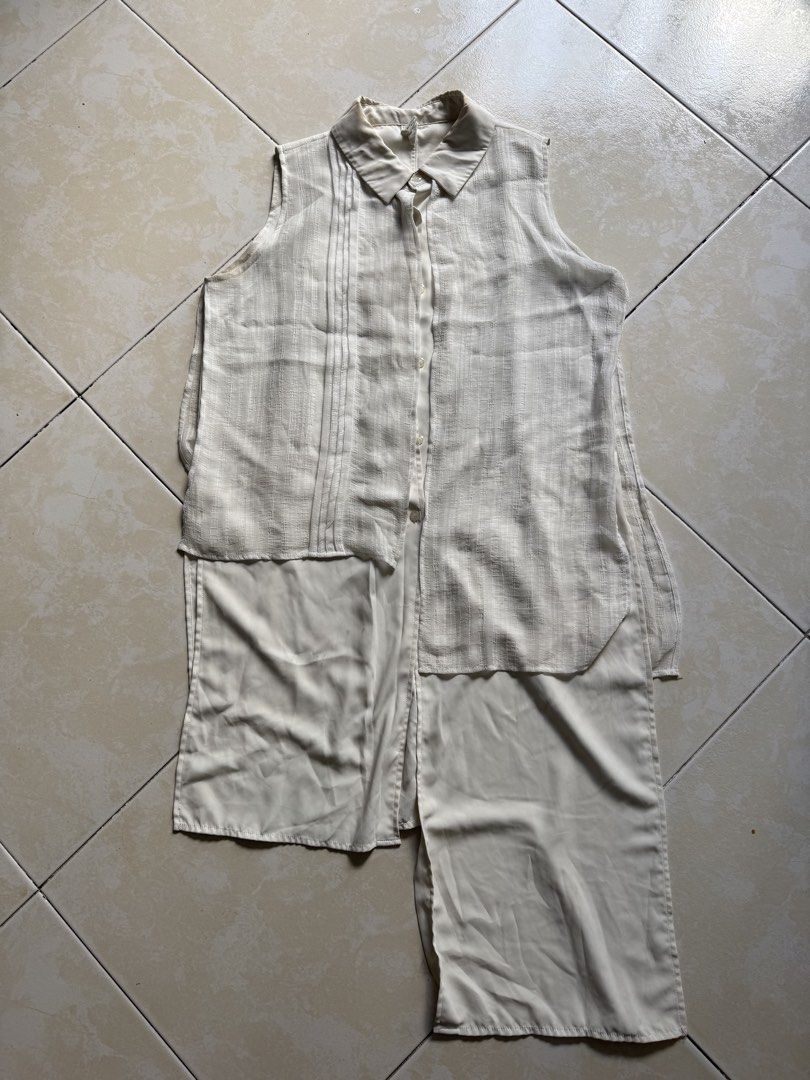 Sleeveless Top with Pleated Detail (Category: Sleeveless) located in Quezon City. Submitted by shndm25 (Listing ID 1424040071, Image 1). Description: - Sleeveless top - Collared neckline - Button-down front - Unique layered design with pleated detail - Long, asymmetrical hemline - Neutral color (beige/cream) - Lightweight fabric.