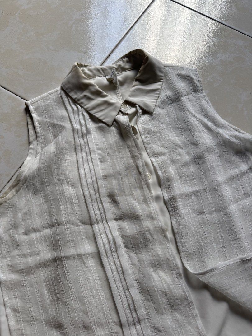Sleeveless Top with Pleated Detail (Category: Sleeveless) located in Quezon City. Submitted by shndm25 (Listing ID 1424040071, Image 3). Description: - Sleeveless top - Collared neckline - Button-down front - Unique layered design with pleated detail - Long, asymmetrical hemline - Neutral color (beige/cream) - Lightweight fabric.