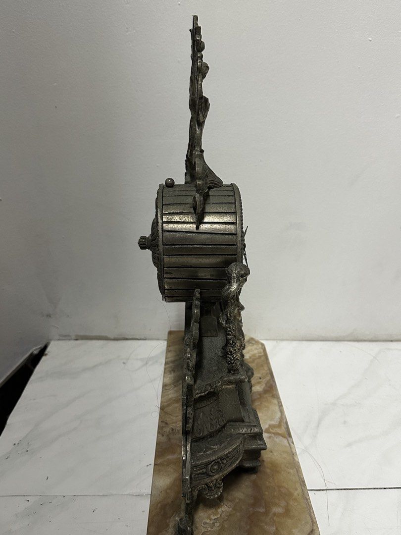 Vintage Decorative Clock (Category: Clocks) located in Quezon City. Submitted by anjherga27 (Listing ID 1423994230, Image 3). Description: - Antique clock - Roman numeral display - Decorative cherub figures - Ornate metal detailing - Elegant marble base - Visible clock mechanism.