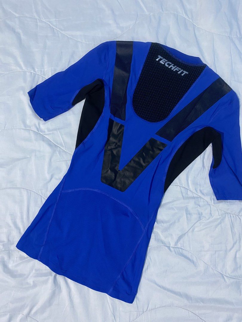 Adidas Techfit Compression Shirt (Category: Activewear) located in Makati City. Submitted by eunaj (Listing ID 1425754431, Image 2). Description: Adidas Techfit compression shirt in blue and black. Features a crew neck and short sleeves. The shirt has a Techfit logo on the back and Adidas logo on the front. It has mesh panels on the shoulders and back for breathability. The shirt is designed for athletic activities. .