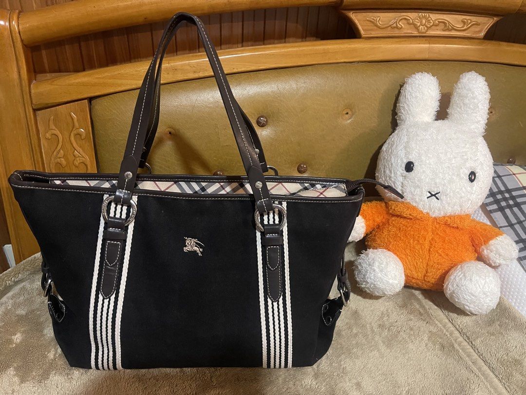 Burberry Blue Label Tote Bag (Category: Luxury Bags & Wallets) located in Subic. Submitted by dani70 (Listing ID 1425768101, Image 2). Description: Preloved Black canvas with leather trim Features vertical cream or white striped webbing on the front and back Often lined with Burberry's signature Nova Check pattern Medium to large size No flaw .