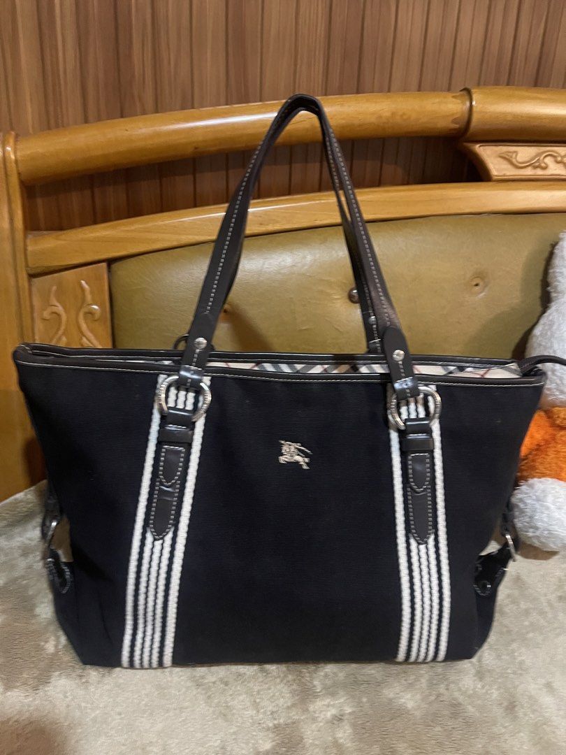 Burberry Blue Label Tote Bag (Category: Luxury Bags & Wallets) located in Subic. Submitted by dani70 (Listing ID 1425768101, Image 1). Description: Preloved Black canvas with leather trim Features vertical cream or white striped webbing on the front and back Often lined with Burberry's signature Nova Check pattern Medium to large size No flaw .