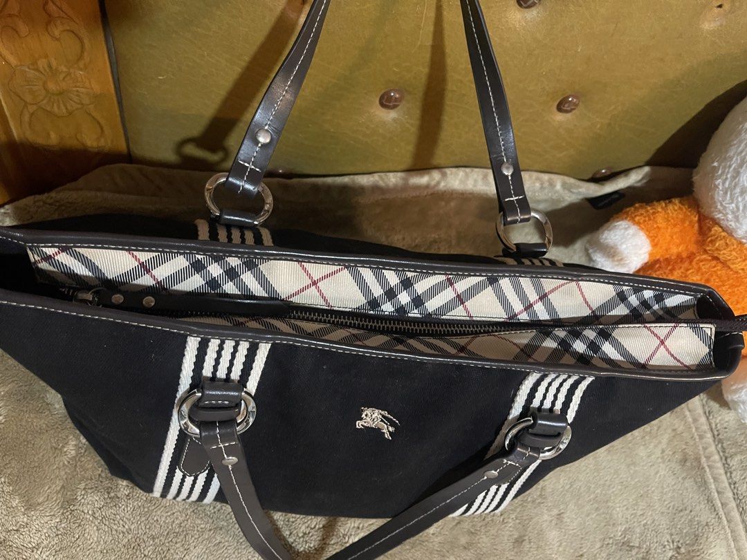 Burberry Blue Label Tote Bag (Category: Luxury Bags & Wallets) located in Subic. Submitted by dani70 (Listing ID 1425768101, Image 3). Description: Preloved Black canvas with leather trim Features vertical cream or white striped webbing on the front and back Often lined with Burberry's signature Nova Check pattern Medium to large size No flaw .