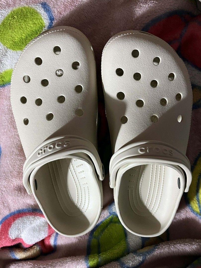 Crocs Classic Clogs - Bone (Category: Slippers & Slides) located in Manila. Submitted by jajaplaza874630 (Listing ID 1425677526, Image 3). Description: Classic Crocs clogs in bone color. Features the Crocs logo on the side and the strap. The clogs have the signature Crocs holes on the top. The clogs are in a neutral color, making them versatile for various outfits..