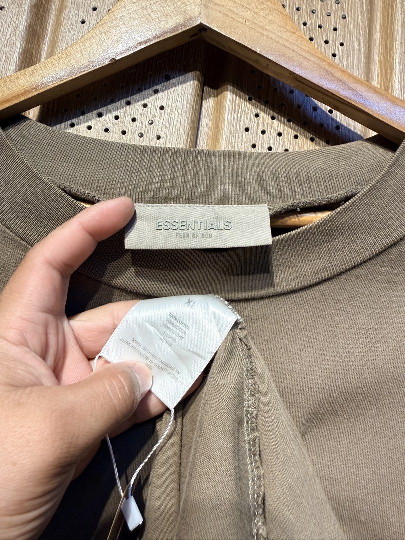 Essentials Fear of God T-shirt XL (Category: Tshirts & Polo Shirts ) located in Santiago. Submitted by twicebutnice03 (Listing ID 1425735900, Image 3). Description: Essentials Fear of God T-shirt is in a brown color. It features the Essentials logo on the front. The size is XL. The tag is visible, confirming the brand and size. Size & dimes: L-XL 24”30.