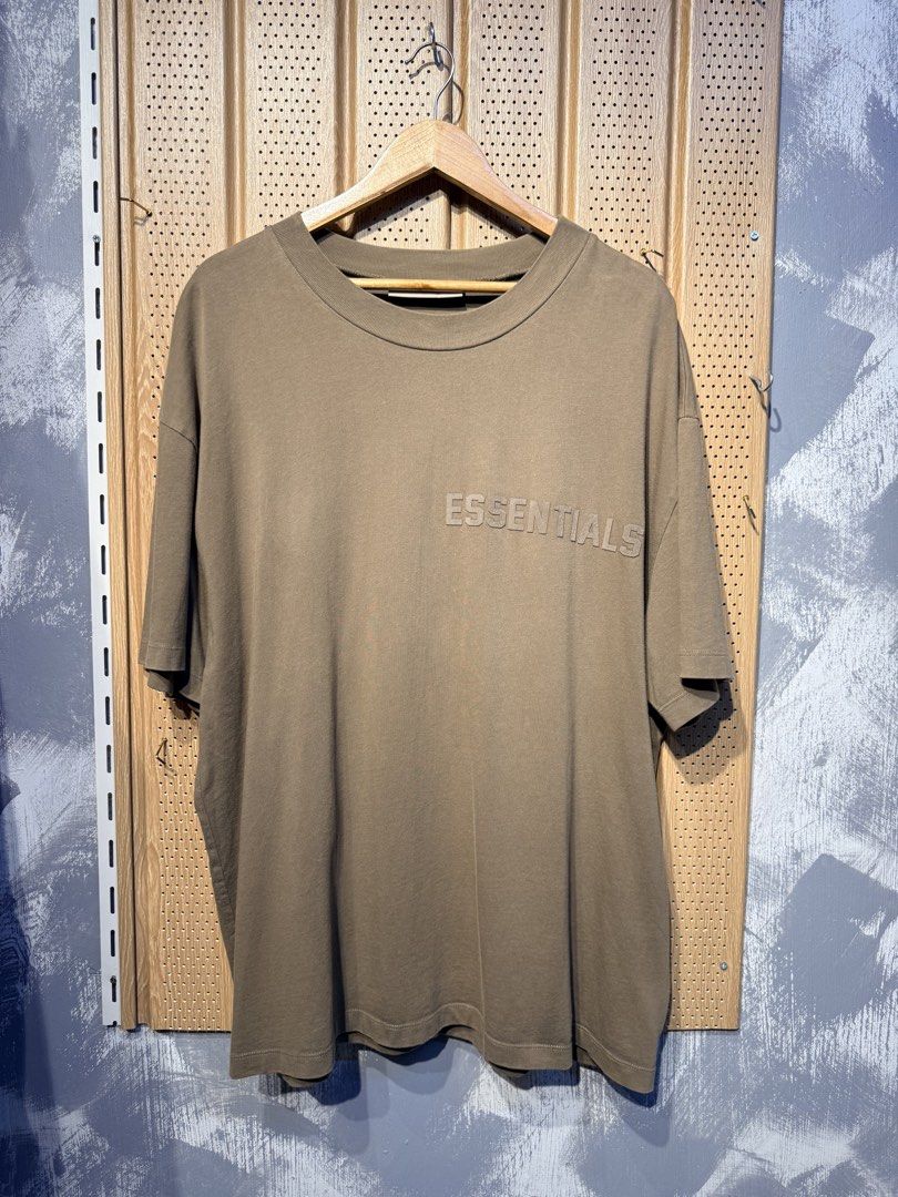 Essentials Fear of God T-shirt XL (Category: Tshirts & Polo Shirts ) located in Santiago. Submitted by twicebutnice03 (Listing ID 1425735900, Image 1). Description: Essentials Fear of God T-shirt is in a brown color. It features the Essentials logo on the front. The size is XL. The tag is visible, confirming the brand and size. Size & dimes: L-XL 24”30.