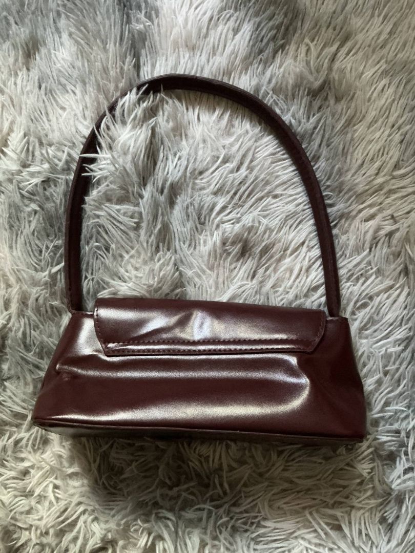 Maroon Shoulder Bag with Gold Clasp (Category: Shoulder Bags) located in San Fernando. Submitted by elixiriaz (Listing ID 1425689552, Image 2). Description: Elegant maroon shoulder bag with a glossy finish. Features a curved handle and a secure gold-colored clasp. The bag has a rectangular shape. The bag is suitable for everyday use. - bought from temu - used once - good as new.