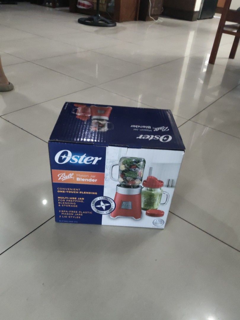 Oster Ball Mason Jar Blender (Category: Juicers, Blenders & Grinders) located in Quezon City. Submitted by gcnt_trift_store (Listing ID 1425658299, Image 2). Description: Oster blender comes with a Ball Mason Jar. It is designed for multi-use applications, including blending, chopping, and making smoothies. The box shows the blender and jar in red. It also includes a recipe book and a flip-top lid for easy pouring..