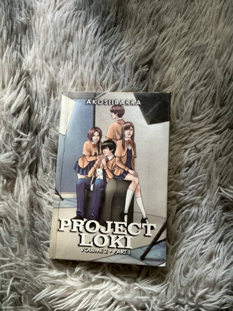 Project Loki Volume 2 Part 1 (Category: Comics & Manga) located in San Fernando. Submitted by elixiriaz (Listing ID 1425686094, Image 1). Description: Project Loki Volume 2 Part 1 manga. Features artwork of characters in school uniforms. The author's name is Akosiibarra. The book is placed on a fluffy, grey surface. The cover art shows a group of students. -barely used but pages have discoloration due to storage .