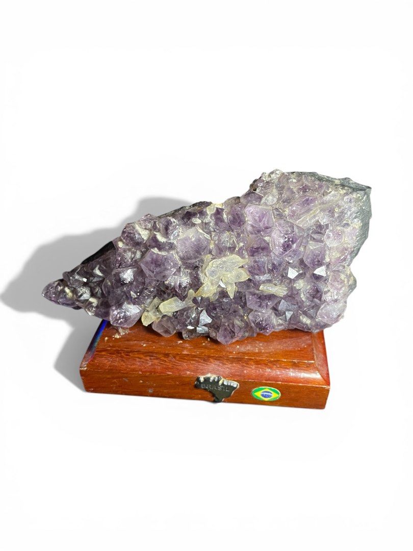 Amethyst Crystal Cluster with Wooden Base (Category: Other Home Decor) located in Compostela. Submitted by cameroncj (Listing ID 1425726909, Image 1). Description: Beautiful amethyst crystal cluster mounted on a wooden base. The crystal features a rich purple hue with visible crystalline structures. The wooden base has a small Brazil flag emblem. A unique decorative piece for any space. 💎 Product Details: • Stone: Natural Amethyst Crystal Cluste