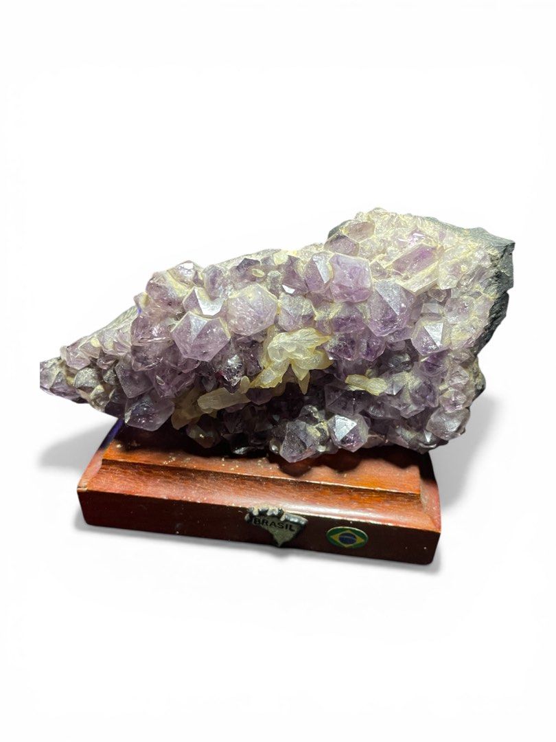 Amethyst Crystal Cluster with Wooden Base (Category: Other Home Decor) located in Compostela. Submitted by cameroncj (Listing ID 1425726909, Image 2). Description: Beautiful amethyst crystal cluster mounted on a wooden base. The crystal features a rich purple hue with visible crystalline structures. The wooden base has a small Brazil flag emblem. A unique decorative piece for any space. 💎 Product Details: • Stone: Natural Amethyst Crystal Cluste