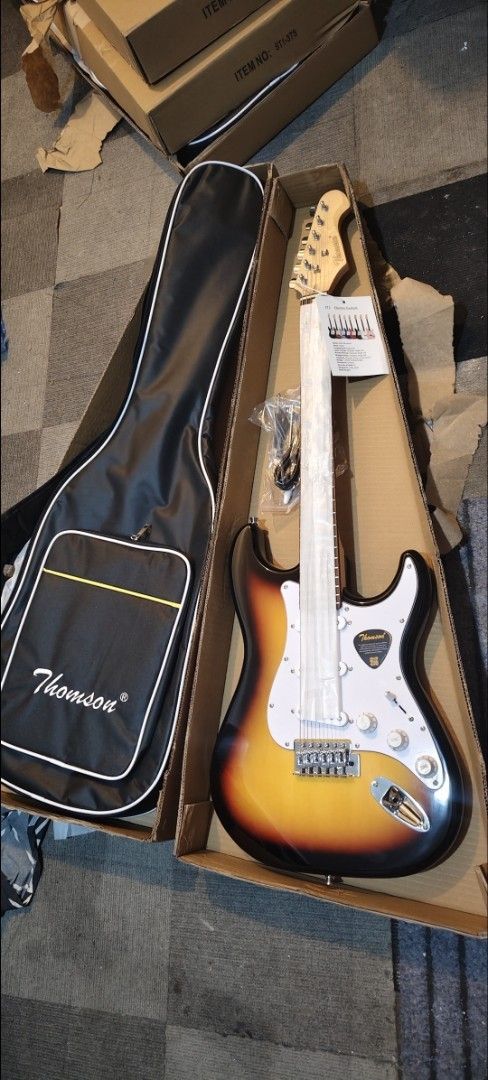 electric guitar Thomson Electric Guitar with Case (Category: Musical Instruments) located in Pasig City. Submitted by tupriomichaeljohn (Listing ID 1425881849, Image 3). Description: Thomson electric guitar with a carrying case. Available in black, sunburst, blue, and brown. Includes a guitar case, cable, and accessories. The guitar has a white pickguard and a maple neck. The headstock has the Thomson logo. Perfect for beginners or experienced pl