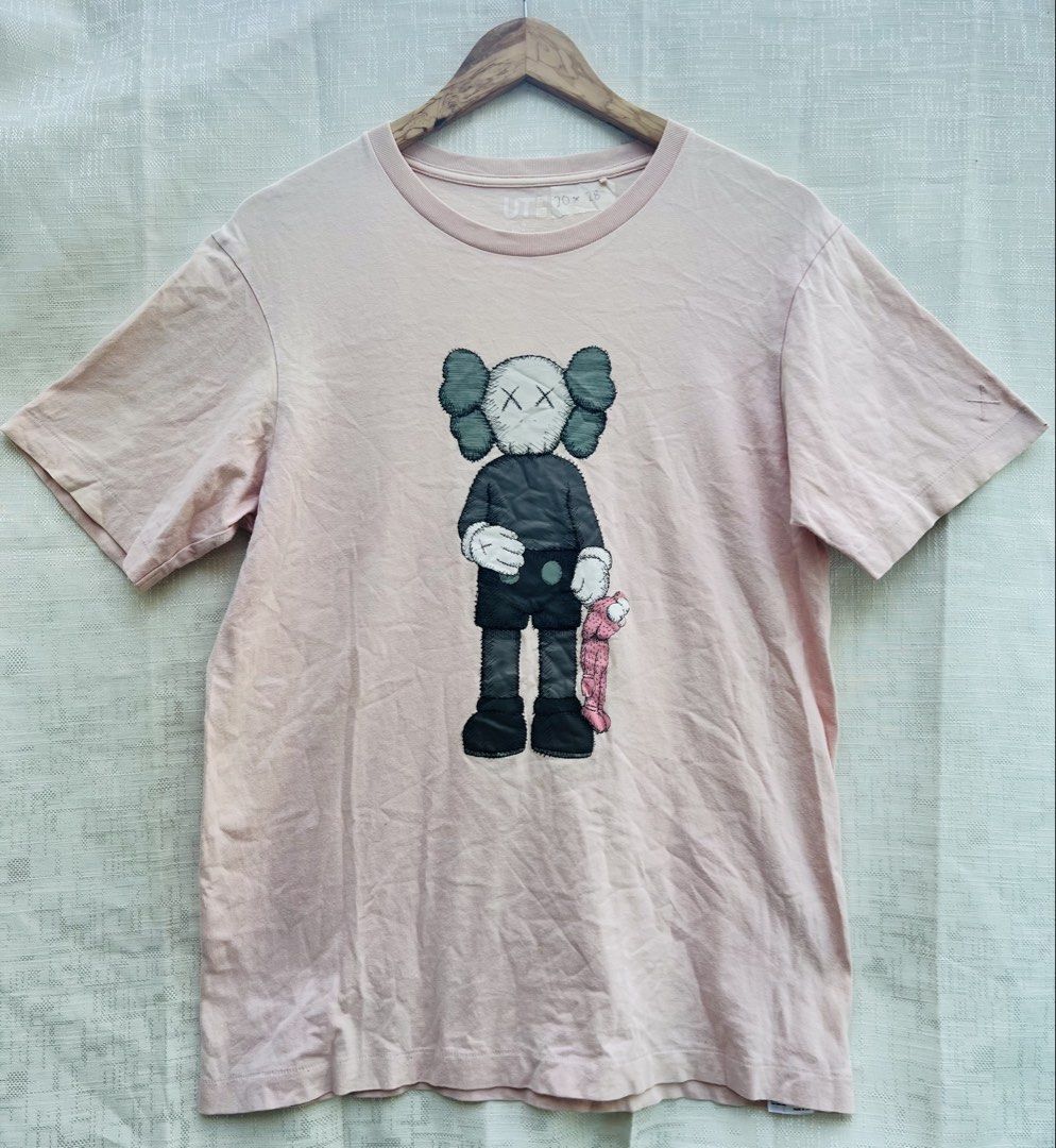 KAWS Pink Graphic T-shirt (Category: Tshirts & Polo Shirts ) located in Rizal. Submitted by thrift_for_styles (Listing ID 1425838044, Image 1). Description: Pink KAWS graphic t-shirt featuring a KAWS character print on the front. The t-shirt has a crew neck and short sleeves. The design includes the iconic KAWS character holding a small pink companion..