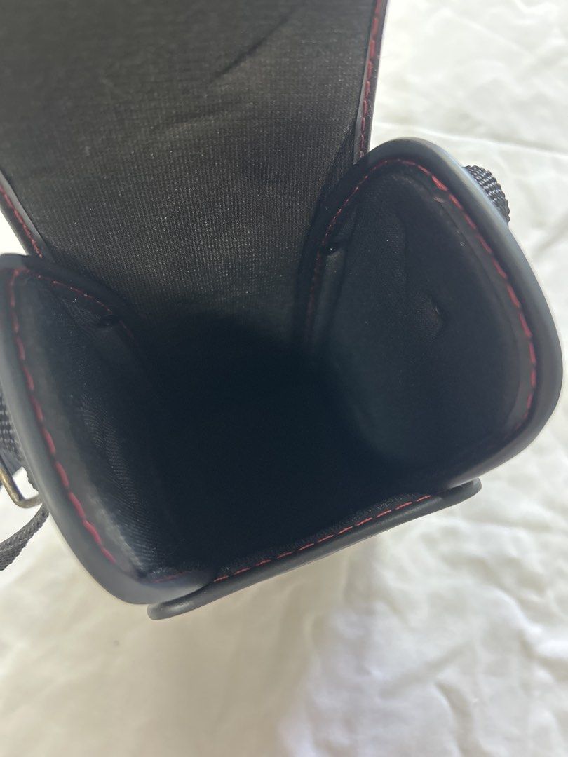 Sigma Camera Case with Strap (Category: Camera Bags & Carriers) located in Bulacan. Submitted by ourdailybreads (Listing ID 1425841402, Image 3). Description: Black Sigma camera case with a red stitched trim. Includes a black strap for carrying. The case has a rectangular shape with a flap closure. The Sigma logo is visible on the front..