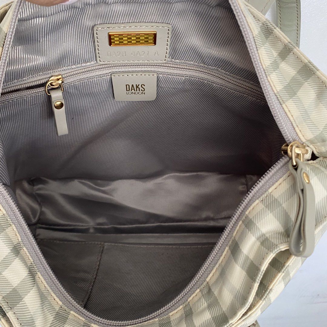 DAKS London Plaid Tote Medium Bag (Category: Tote Bags) located in Roxas City. Submitted by rglnos (Listing ID 1426020078, Image 3). Description: DAKS London tote bag features a classic plaid pattern in neutral tones. It has a top zipper closure and a spacious interior. The bag includes a small interior pocket and a magnetic snap closure. The handles and trim are a matching solid color. The bag has a metal DAKS logo on the front..