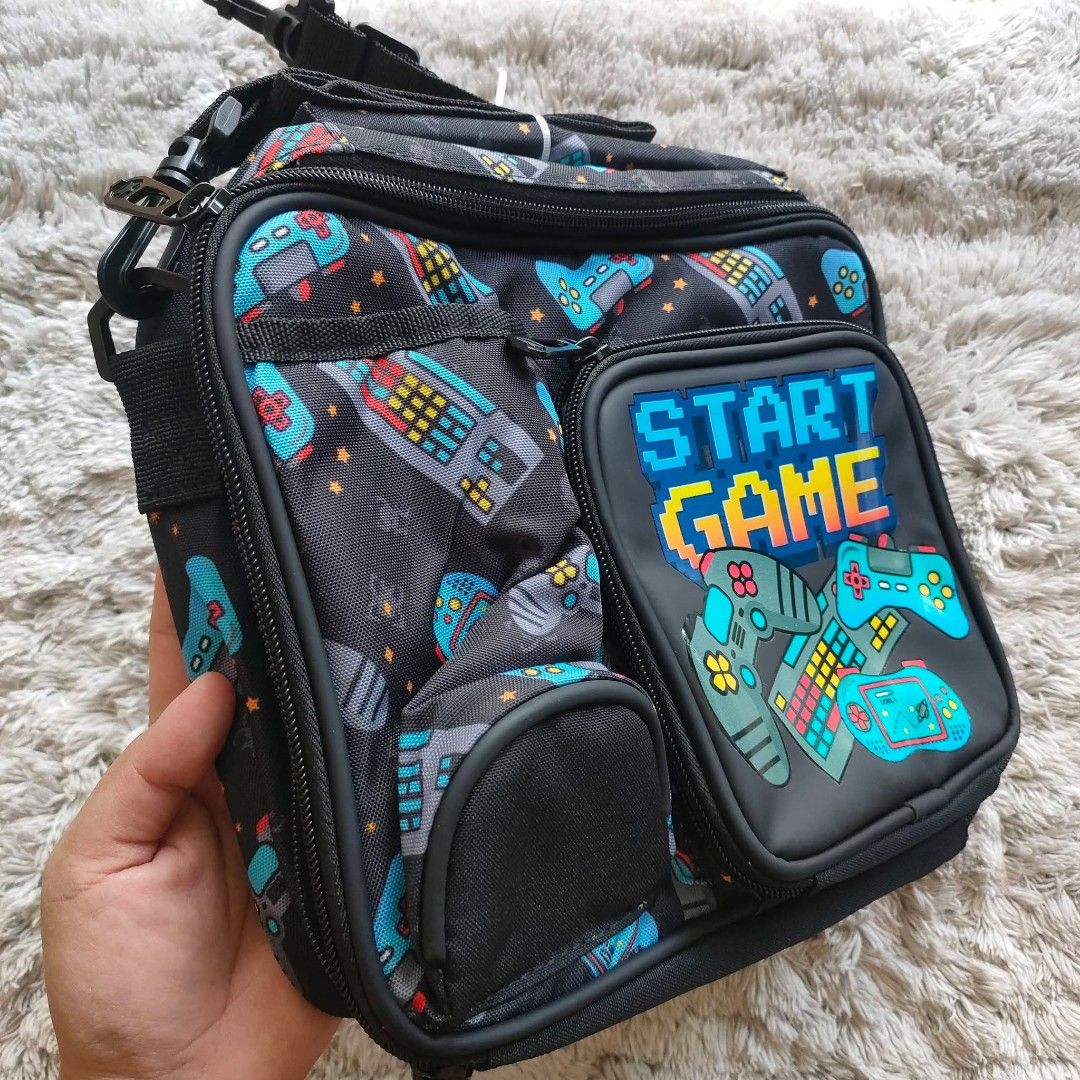 Insulated lunch bag boys (Category: Other Babies Going Out Needs) located in Manila. Submitted by rach0122 (Listing ID 1426183034, Image 2). Description: Lunch bag features a fun gaming theme with controller and keyboard designs. It has multiple compartments, including a front pocket and a main insulated compartment. The bag also has a shoulder strap for easy carrying. Perfect for school or work, it keeps your food fresh and organized..