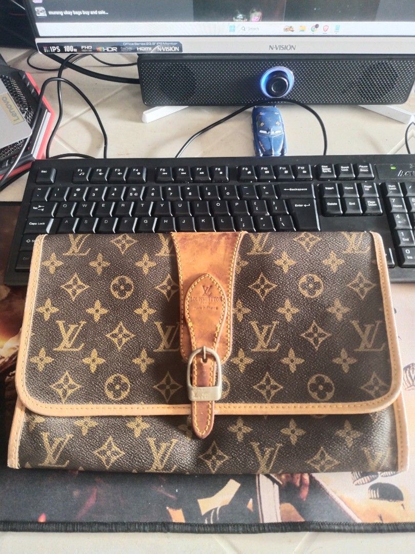 Louis Vuitton Clutch Bag (Category: Luxury Bags & Wallets) located in Valencia. Submitted by coolwolf_27a64f (Listing ID 1426062072, Image 1). Description: Japan Surplus Authentic Louis Vuitton clutch bag. Features the iconic monogram pattern. Includes a leather strap with a buckle closure. The interior has a leather lining and a zipper. Made in France. Issue Rubs over all good.
