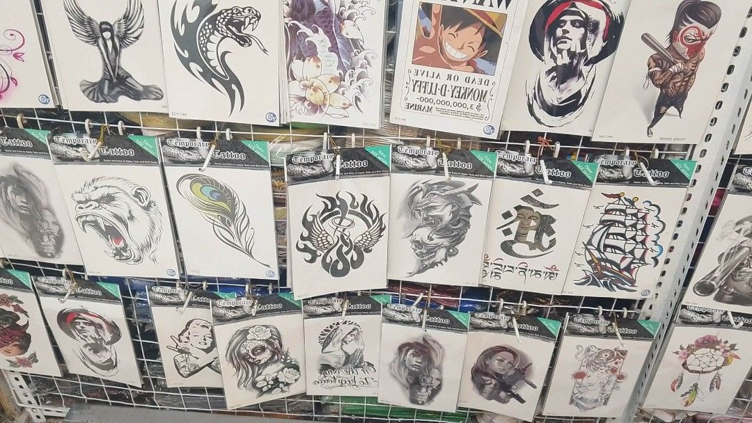 Temporary Tattoo Assortment - Various Designs (Category: Art & Prints) located in Manila. Submitted by neojamesca55018 (Listing ID 1426182170, Image 2). Description: Wide variety of temporary tattoos featuring diverse designs. Includes images of eagles, hands, roses, anime characters, and tribal patterns. Each tattoo is individually packaged. Designs include both black and white and colored options. Perfect for adding some flair to your look. Gre