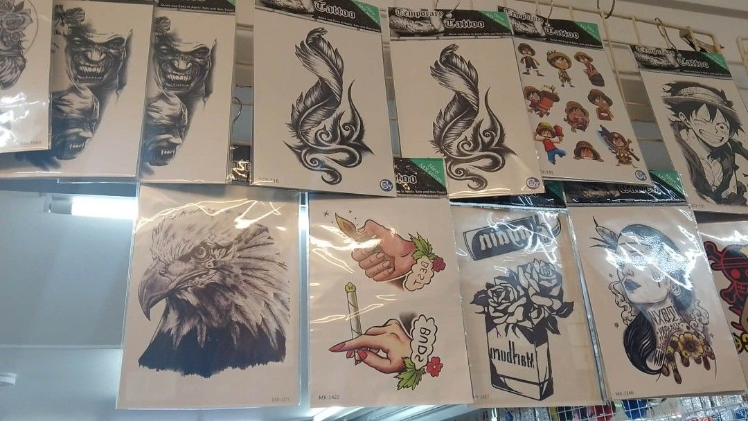 Temporary Tattoo Assortment - Various Designs (Category: Art & Prints) located in Manila. Submitted by neojamesca55018 (Listing ID 1426182170, Image 1). Description: Wide variety of temporary tattoos featuring diverse designs. Includes images of eagles, hands, roses, anime characters, and tribal patterns. Each tattoo is individually packaged. Designs include both black and white and colored options. Perfect for adding some flair to your look. Gre
