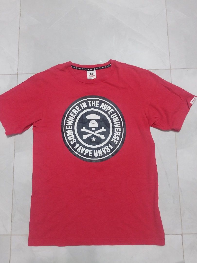 Aape by A Bathing Ape Red T-shirt (Category: Tshirts & Polo Shirts ) located in Malaybalay. Submitted by markdaumar08466 (Listing ID 1426301519, Image 1). Description: Authentic Aape by A Bathing Ape red t-shirt. Features a large graphic on the front with the text "IN THE AAPE UNIVERSE SOMEWHERE IN AAPE". The shirt has a small Aape logo on the sleeve. The tag indicates the shirt is made of 100% cotton..