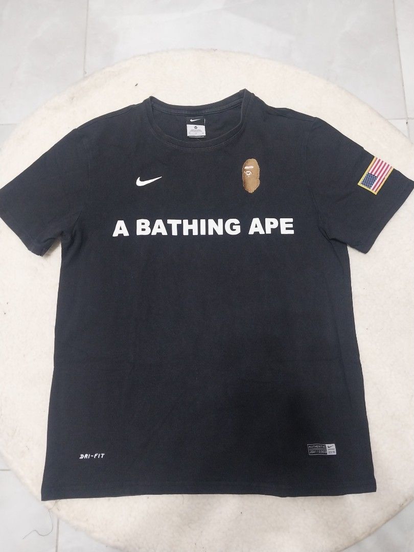 BAPE x Nike Shark Tee (Category: Tshirts & Polo Shirts ) located in Malaybalay. Submitted by markdaumar08466 (Listing ID 1426215987, Image 1). Description: Black BAPE x Nike t-shirt featuring the iconic shark design on the back and the BAPE logo on the front. It has a small Nike logo on the chest. The shirt has an American flag patch on the sleeve. It is a Dri-FIT shirt..