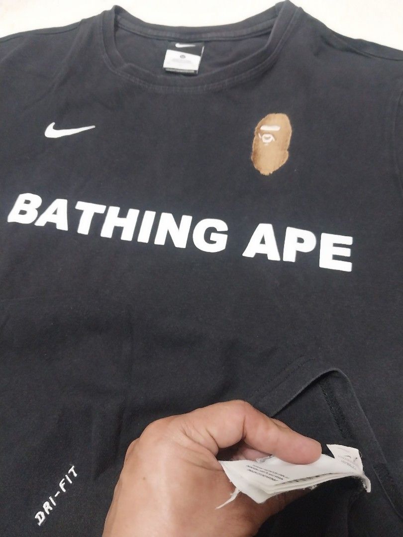 BAPE x Nike Shark Tee (Category: Tshirts & Polo Shirts ) located in Malaybalay. Submitted by markdaumar08466 (Listing ID 1426215987, Image 3). Description: Black BAPE x Nike t-shirt featuring the iconic shark design on the back and the BAPE logo on the front. It has a small Nike logo on the chest. The shirt has an American flag patch on the sleeve. It is a Dri-FIT shirt..