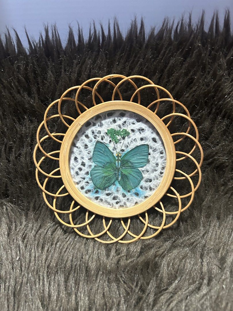 Butterfly Wall Decor with Rattan Frame (Category: Wall Decor) located in Angeles City. Submitted by zyeplustradings (Listing ID 1426382404, Image 1). Description: Unique wall decor features a beautiful butterfly design encased in a round frame. The frame is made of woven rattan, adding a natural and textured element. The butterfly is a vibrant teal color, set against a white background. It's a charming piece that can add a touch of nature-inspire