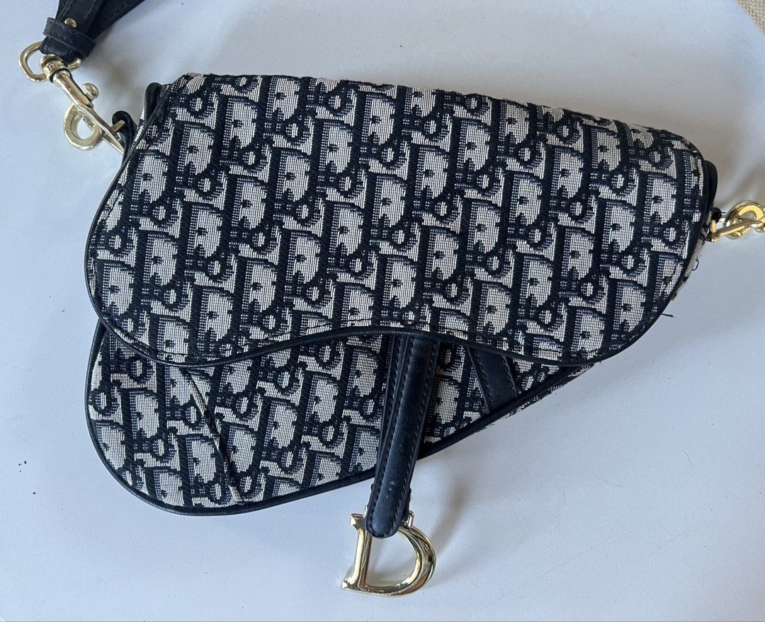Christian Dior Saddle Bag not auth (Category: Luxury Bags & Wallets) located in Cabanatuan. Submitted by jandjarmoire (Listing ID 1426215189, Image 2). Description: NOT AUTHENTIC Christian Dior Saddle Bag. Features the iconic Dior Oblique canvas and a detachable shoulder strap with the Christian Dior logo. The bag has a curved shape with a 'D' charm on the flap. The interior includes a zippered pocket. Gold-tone hardware is visible on the strap a
