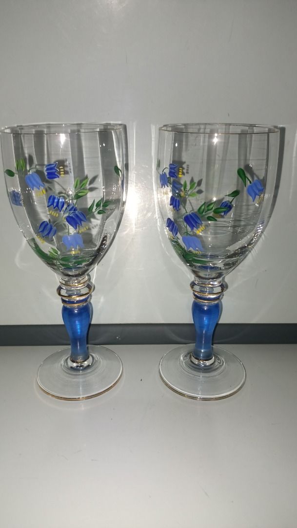 Hand-Painted Floral Wine Glasses (Category: Dinnerware & Cutlery) located in Munoz. Submitted by larryc1212 (Listing ID 1426225530, Image 1). Description: Set of two elegant wine glasses featuring hand-painted blue floral designs. Each glass has a blue stem with gold accents. The glasses are approximately 7 inches tall. Perfect for serving wine or as a decorative piece. The glasses have a clear bowl and a delicate, detailed design. Item may inclu