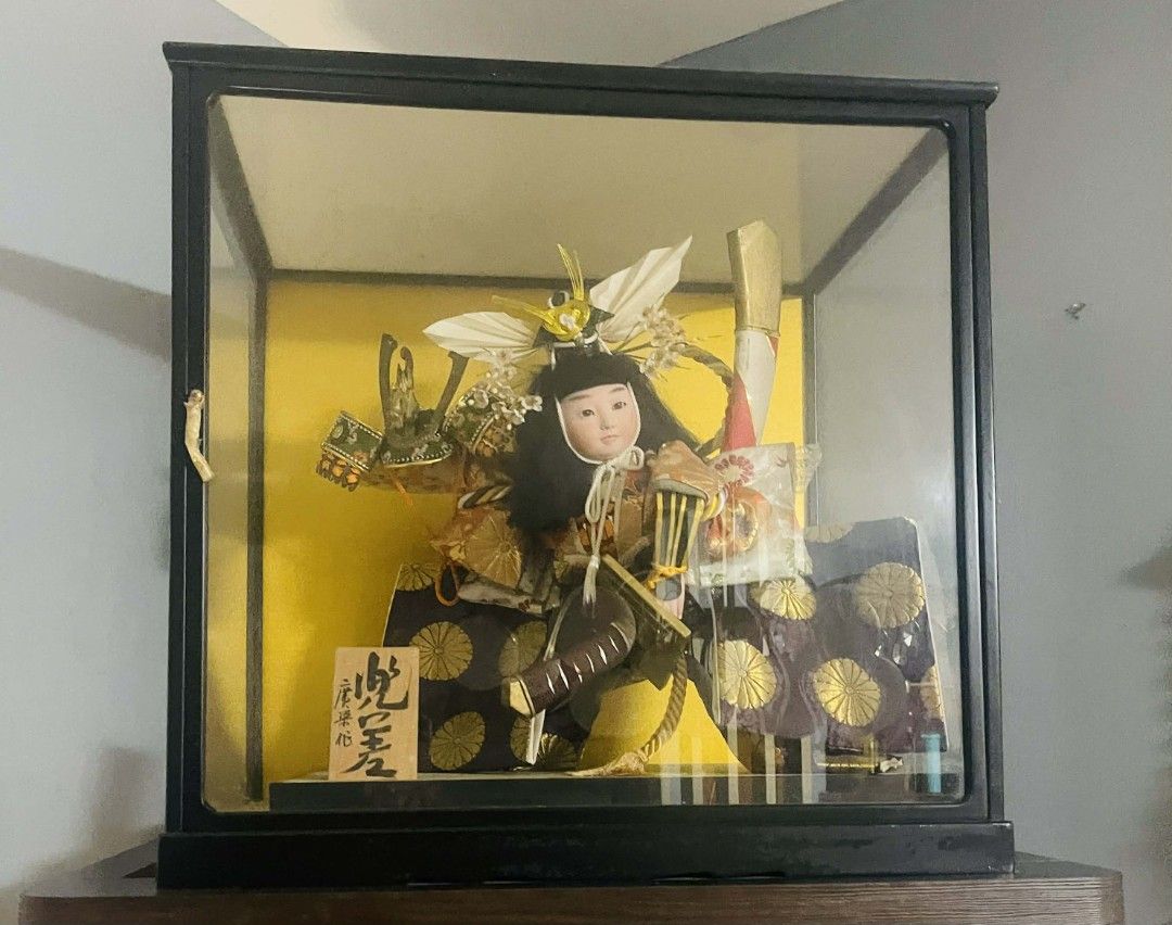 Japanese Samurai Doll in Display Case (Category: Vintage Collectibles) located in Manila. Submitted by cloestore (Listing ID 1426269706, Image 1). Description: - Authentic Japanese samurai doll - Displayed in a glass case - Dressed in traditional samurai armor and helmet - Set against a yellow backdrop - Black-framed display case - Includes a small wooden sign with Japanese characters.