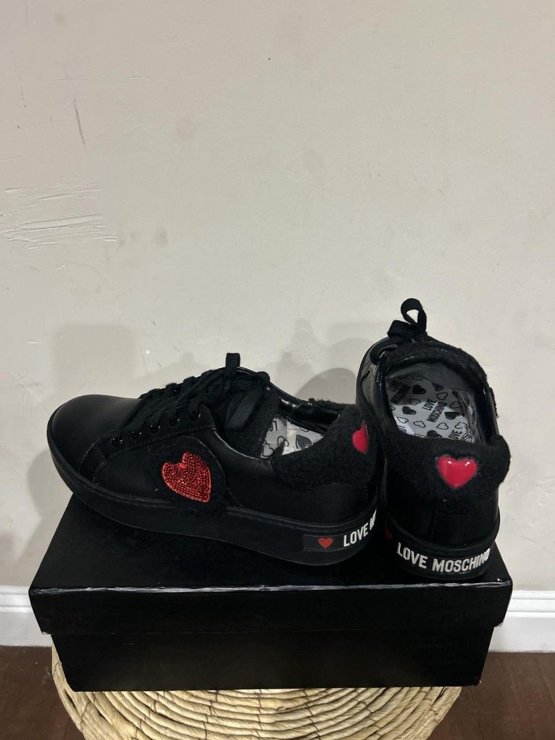Love Moschino Black Sneakers (Category: Sneakers) located in Quezon City. Submitted by plus4lessshop (Listing ID 1426357234, Image 3). Description: Black Love Moschino sneakers with a heart design. The sneakers have black laces and a black sole. The Love Moschino logo is visible on the side and the back of the shoe. The shoes come with the original box..