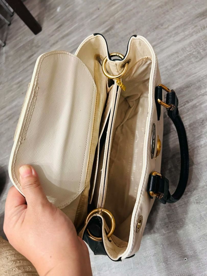 metrocity handbag (Category: Luxury Bags & Wallets) located in Batangas. Submitted by selahs-closet (Listing ID 1426248975, Image 3). Description: Handbag features a two-tone design with black and cream colors. It has black handles and gold-colored hardware. The bag has a central emblem and a clasp closure. Inside, there are multiple compartments for organization..