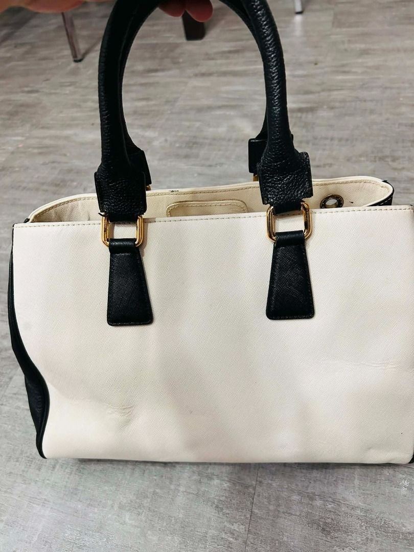 metrocity handbag (Category: Luxury Bags & Wallets) located in Batangas. Submitted by selahs-closet (Listing ID 1426248975, Image 2). Description: Handbag features a two-tone design with black and cream colors. It has black handles and gold-colored hardware. The bag has a central emblem and a clasp closure. Inside, there are multiple compartments for organization..