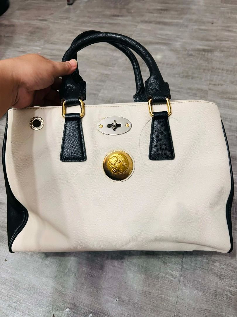 metrocity handbag (Category: Luxury Bags & Wallets) located in Batangas. Submitted by selahs-closet (Listing ID 1426248975, Image 1). Description: Handbag features a two-tone design with black and cream colors. It has black handles and gold-colored hardware. The bag has a central emblem and a clasp closure. Inside, there are multiple compartments for organization..
