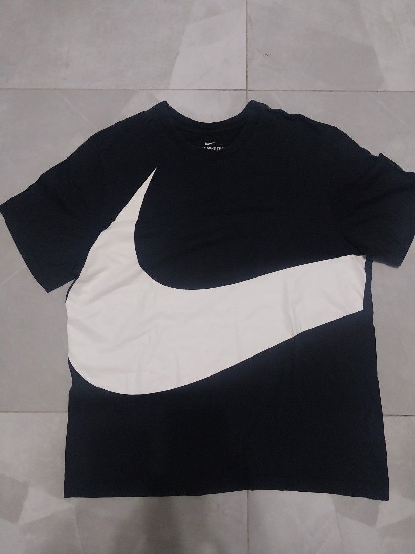 Nike Tee with Large Swoosh (Category: Tshirts & Polo Shirts ) located in Malaybalay. Submitted by markdaumar08466 (Listing ID 1426304178, Image 1). Description: Black Nike T-shirt featuring a large white Swoosh logo. The shirt has a crew neck and short sleeves. The tag indicates it is a Nike Tee. The size is indicated on the tag. Made in China..