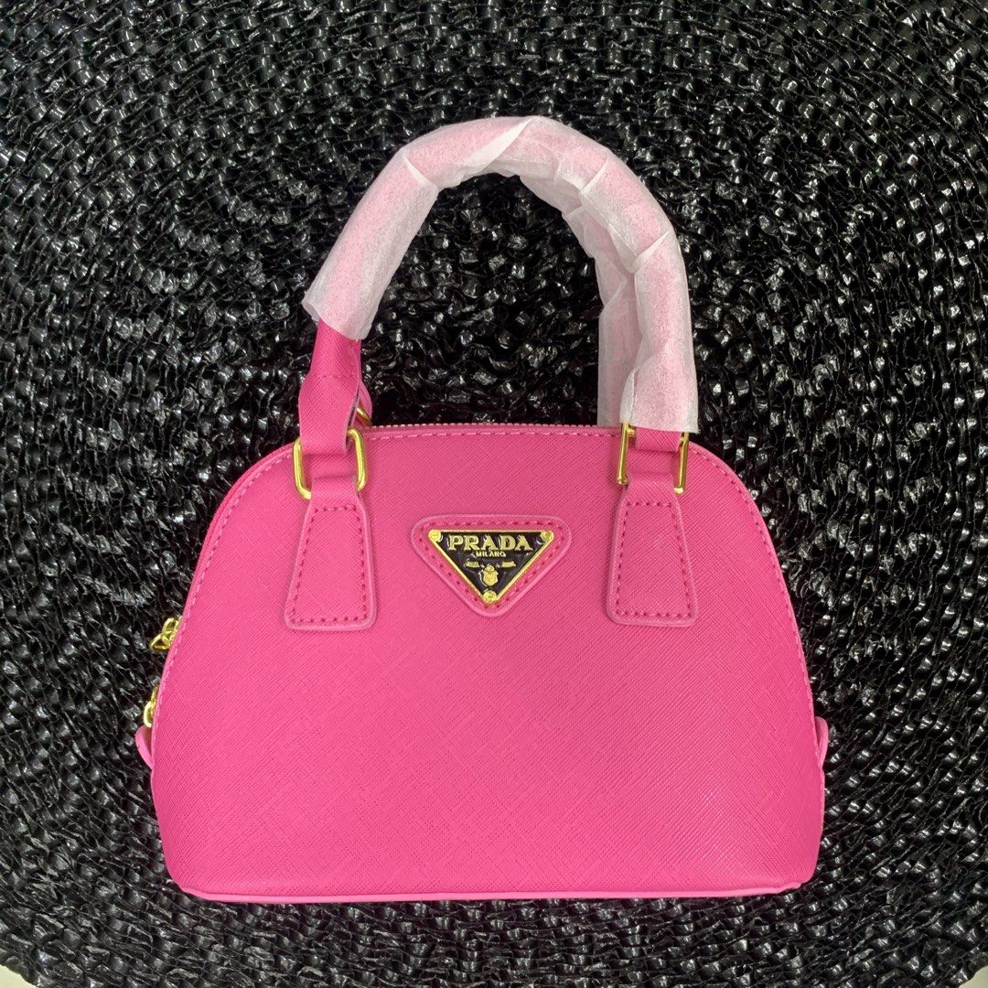 Prada Mini Dome Handbag - Pink (Category: Luxury Bags & Wallets) located in Pasig City. Submitted by paymelikelandlord (Listing ID 1426332211, Image 1). Description: Mini dome handbag from Prada features a vibrant pink color and gold-tone hardware. It has a top handle and a detachable shoulder strap. The interior includes a small pocket and a Prada label. The bag has a zip closure and the Prada logo is visible on the front. As new condition with 