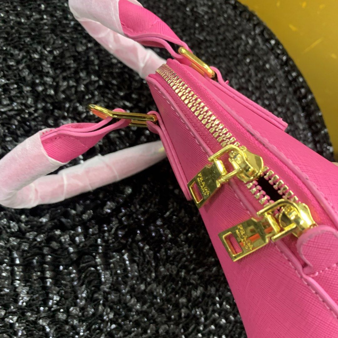 Prada Mini Dome Handbag - Pink (Category: Luxury Bags & Wallets) located in Pasig City. Submitted by paymelikelandlord (Listing ID 1426332211, Image 3). Description: Mini dome handbag from Prada features a vibrant pink color and gold-tone hardware. It has a top handle and a detachable shoulder strap. The interior includes a small pocket and a Prada label. The bag has a zip closure and the Prada logo is visible on the front. As new condition with 