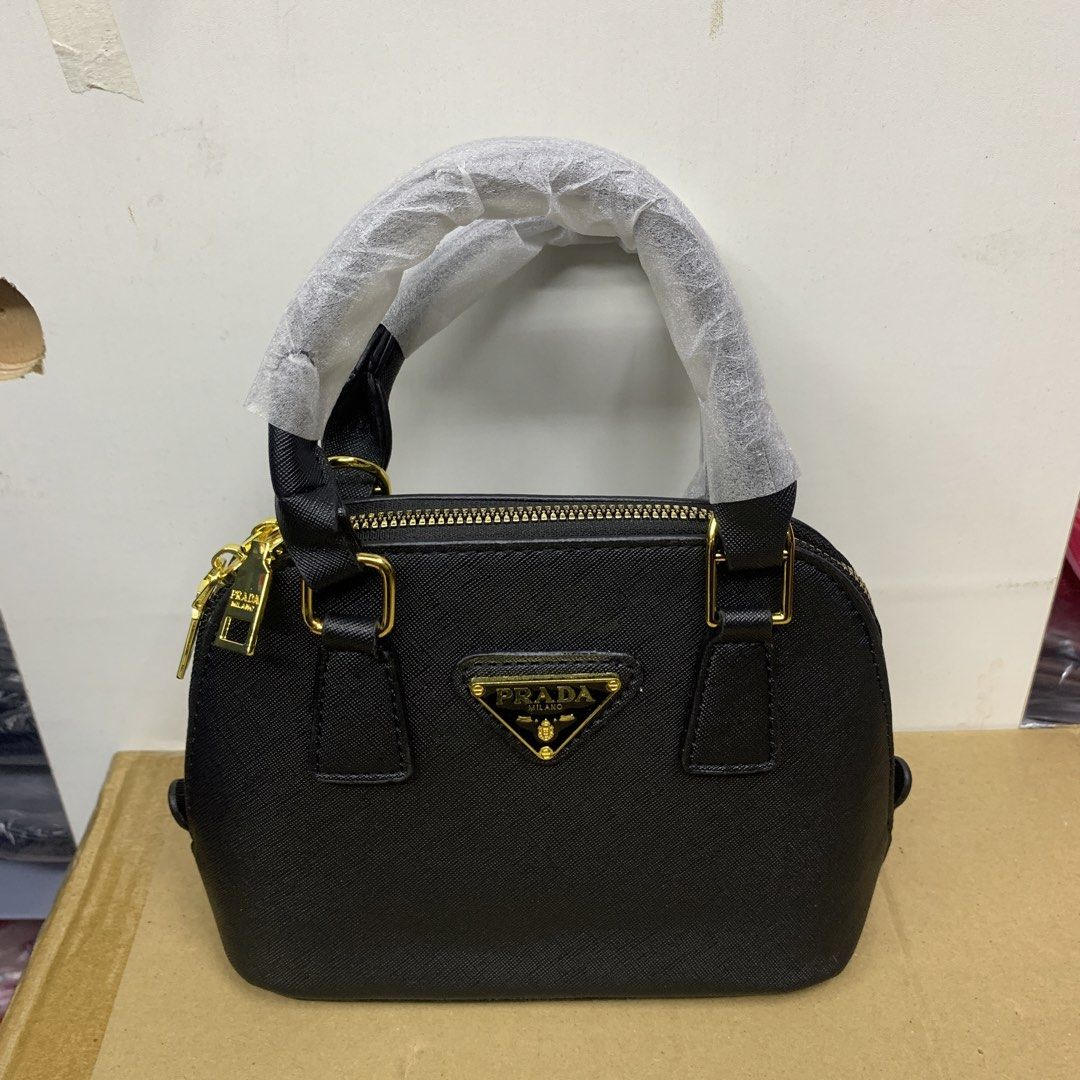 Prada Mini Dome Handbag bag (Category: Luxury Bags & Wallets) located in Pasig City. Submitted by paymelikelandlord (Listing ID 1426342224, Image 1). Description: Black mini dome handbag by Prada. Features a top handle and a detachable shoulder strap. The bag has a gold-tone zipper and hardware. The interior includes a small pocket and a Prada label. Authentic Quality🚀 Quezon City area COD VIA LALAMOVE AROUNG METRO MANILA FREE SHIPPING VIA J&T E