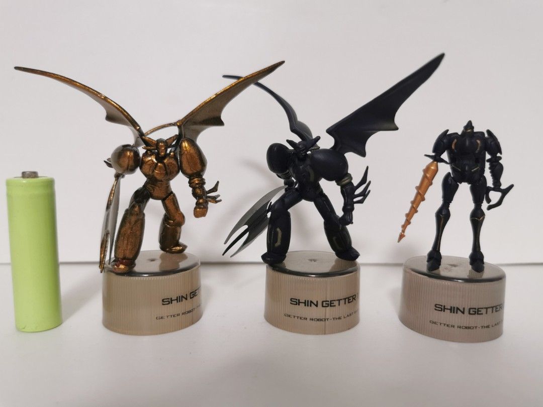 Shin Getter Robot Action Figures black edition (Category: Figurines & Statues) located in Paranaque City. Submitted by planet4k (Listing ID 1426268064, Image 1). Description: Set of three Shin Getter Robot action figures. Each figure is mounted on a base with the Shin Getter Robot logo. The figures have different designs and colors, including gold, black, and a drill-like weapon. The figures appear to be made of metal or a similar material..