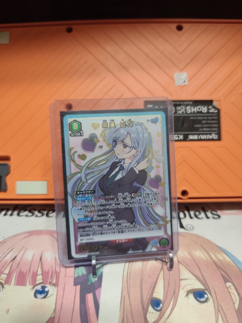Union arena 100 kanojo (Category: Raw Singles) located in Valenzuela. Submitted by hadofakustore (Listing ID 1426233939, Image 1). Description: Weiss Schwarz trading card featuring an anime character. The card is in a protective sleeve. The card has Japanese text and a colorful design. The card is held by a stand. The background includes a keyboard and an anime-themed playmat..