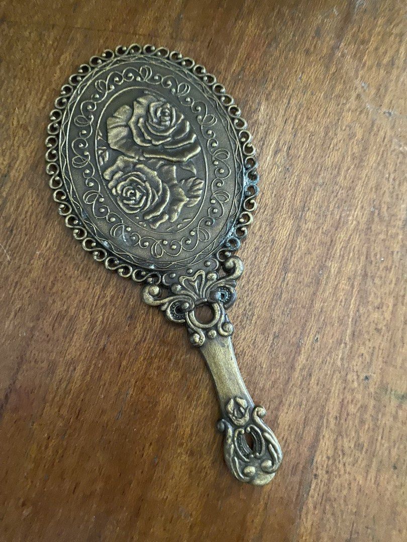 Vintage Oval Hand Mirror with Rose Design (Category: Mirrors) located in Cavite. Submitted by msandysgoodies (Listing ID 1426227938, Image 2). Description: Elegant vintage hand mirror with an oval shape. Features a decorative frame and handle with a rose design on the back. The mirror measures 18 cm in length and 8 cm in width. The handle has a decorative design at the end. The mirror is made of metal with a bronze color..