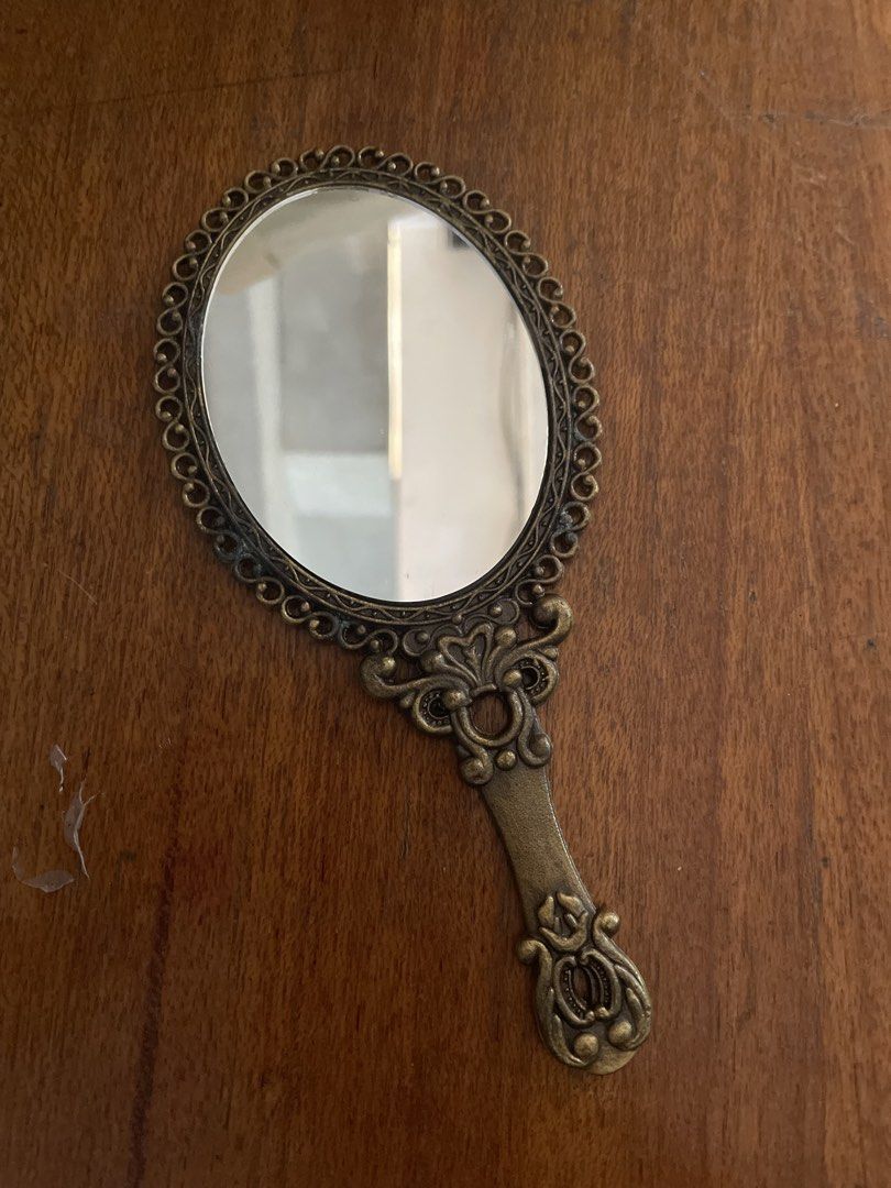 Vintage Oval Hand Mirror with Rose Design (Category: Mirrors) located in Cavite. Submitted by msandysgoodies (Listing ID 1426227938, Image 1). Description: Elegant vintage hand mirror with an oval shape. Features a decorative frame and handle with a rose design on the back. The mirror measures 18 cm in length and 8 cm in width. The handle has a decorative design at the end. The mirror is made of metal with a bronze color..